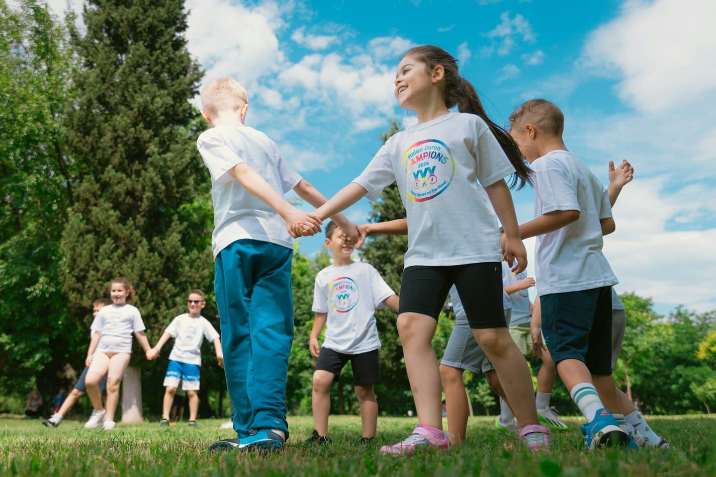 Niños con camisetas a juego se toman de la mano mientras juegan al aire libre.