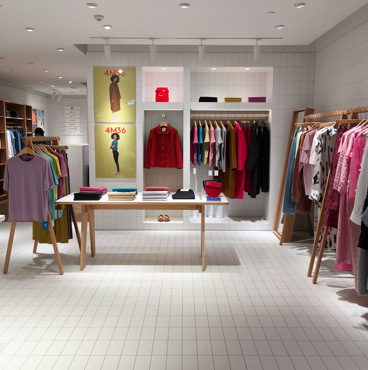 Interior de tienda de ropa moderna con prendas en percheros y mesa de exhibición.