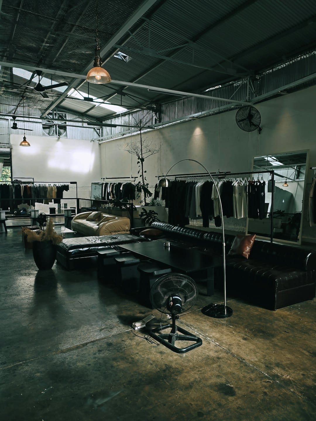 Boutique de ropa moderna con percheros y asientos de cuero sobre pisos de concreto.
