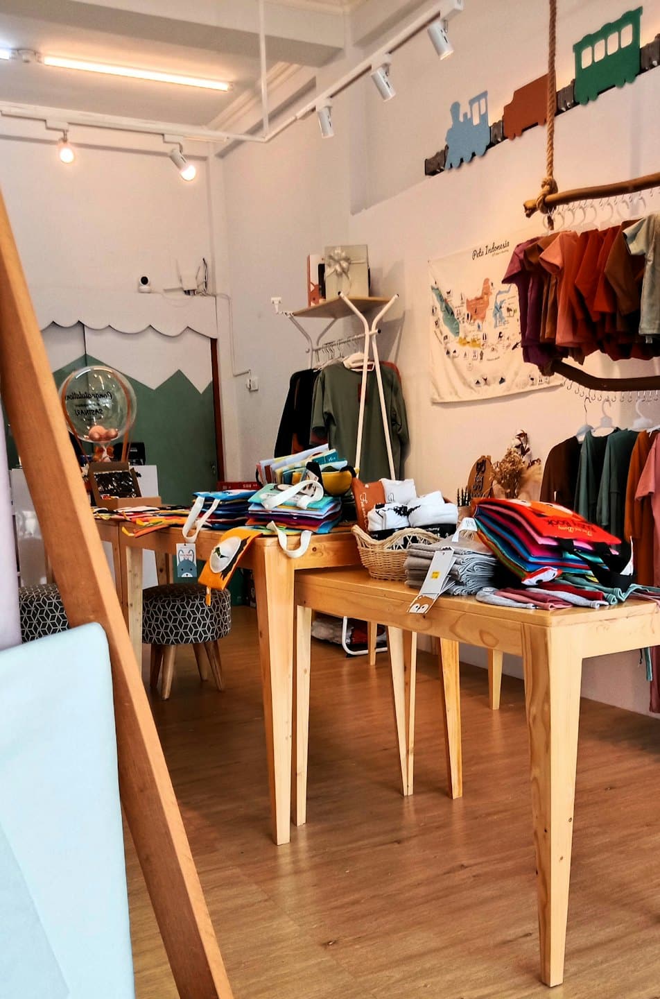 Tienda infantil con mesas de madera que exhiben ropa doblada y accesorios.